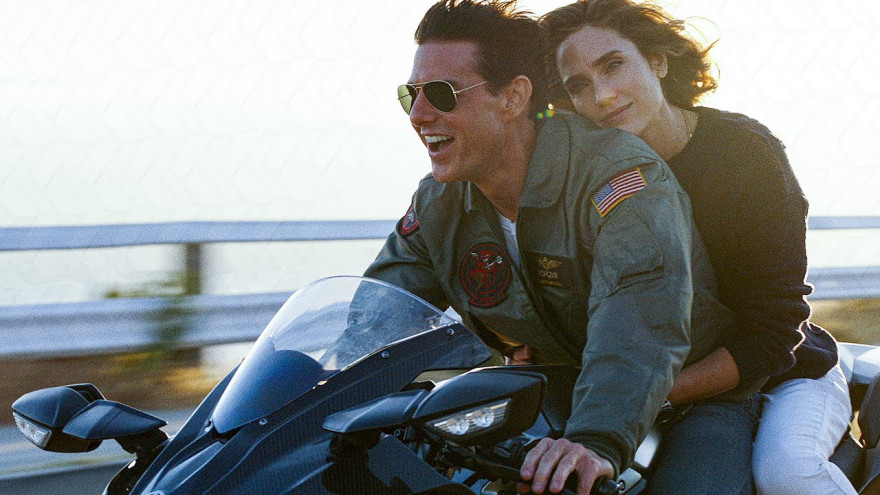 Nasmejani Tom Cruise na Kawasaki motorju. Za njim sedi Jennifer Connelly z zasanjanim pogledom.